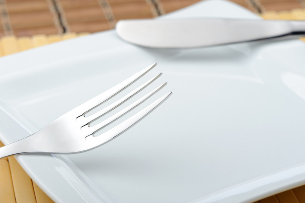 Fork and a knife laying on a plate - Photo, Image