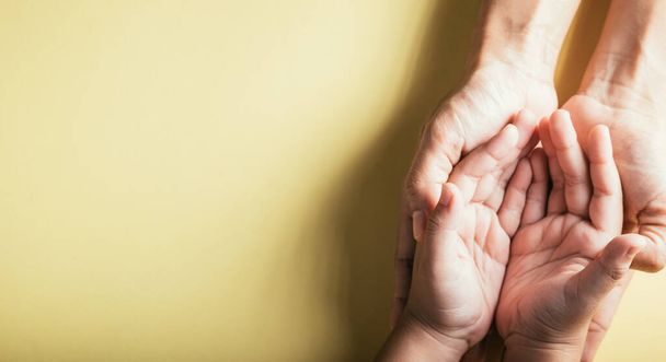 Close up hands children on adult mother hand, Top view person kid stack mom palms, Parents and little kid holding empty hands together isolated on yellow background, Family day care concept - Fotó, kép