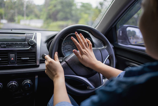 Vrouw duwen hoorn tijdens het rijden zitten van een stuurwiel pers auto, toeteren geluid om andere mensen te waarschuwen in het verkeer concept. - Foto, afbeelding