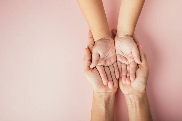 Close up hands children on adult mother hand, Top view person kid stack mom palms, Parents and little kid holding empty hands together isolated on pink background, Family day care concept - Фото, зображення