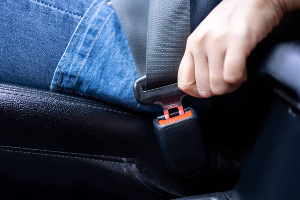 Close-up of a female driver fastens her seat belt before driving. Safe travel concept - Foto, Bild