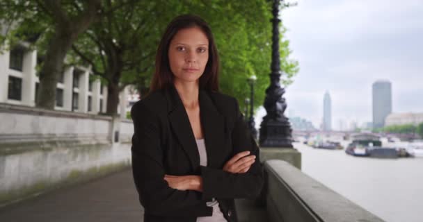 Porträt einer jungen Geschäftsfrau, die die Arme verschränkt und in London an der Themse in die Kamera blickt. Selbstbewusster Millennial-Profi, der Blickkontakt in der Stadt herstellt. 4k - Filmmaterial, Video