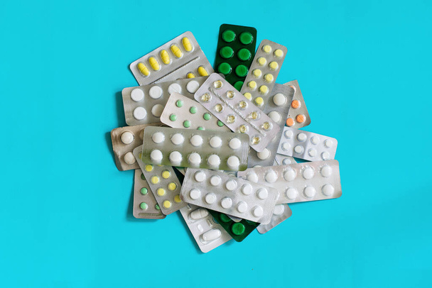 Pila de varias píldoras con el gabinete casero de la medicina sobre fondo azul, analgésicos, píldoras coloreadas, medicina en tabletas - Foto, imagen
