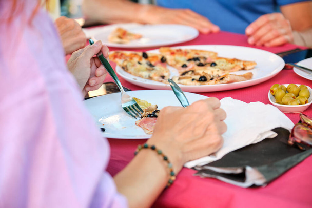 Felismerhetetlen, érett felnőttek pizzát esznek egy étteremben. Névtelen emberek egy bárban.. - Fotó, kép