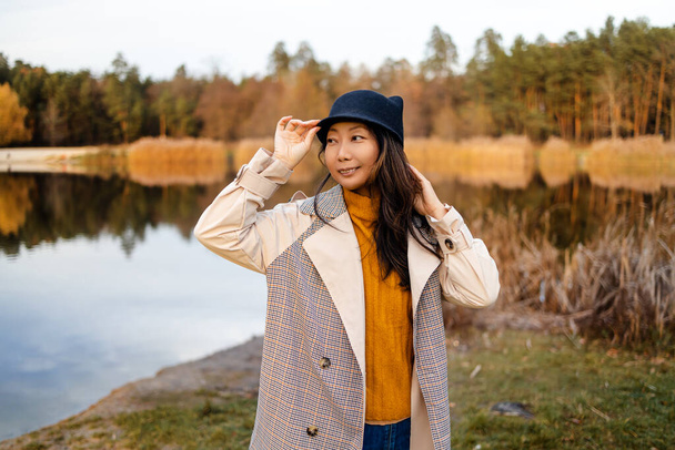 Yksinäinen aasialainen nainen syksyllä metsässä järven kanssa. Syksyn maisema, rauhallisuus, rauhallisuus, matkustaminen. - Valokuva, kuva