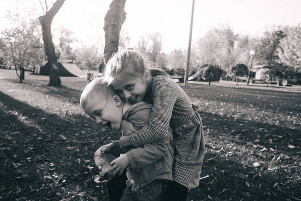 Brat i siostra w parku. Chłopiec i dziewczyna trzymają się za ręce i biegną ścieżką parku. Koncepcja szczęśliwego dzieciństwa i heteroseksualnych krewnych. Promienie słoneczne i liście żółte - Zdjęcie, obraz