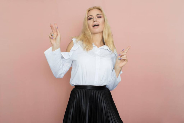 Beauty, fashion portrait. Elegant business style. Portrait of a beautiful blonde woman in white blouse and black skirt posing at studio on a pink background. - Fotografie, Obrázek