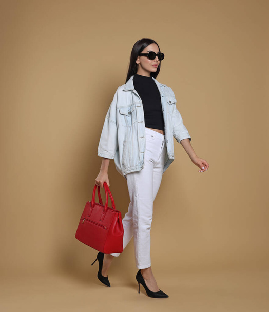 Young woman with stylish bag on beige background - Foto, Imagem