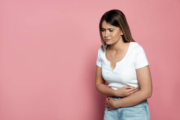 Young woman suffering from menstrual pain on pink background, space for text - Foto, Imagen