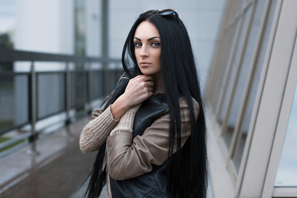 Girl in a leather jacket standing near the building - Fotoğraf, Görsel