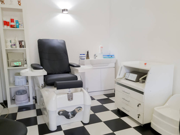 Cadeira de pedicure de couro preto com equipamento profissional na sala de salão de beleza. Mobiliário para salões de pedicure. Spa de pés. QUIIV, UCRÂNIA - OUTUBRO, 2022 - Foto, Imagem