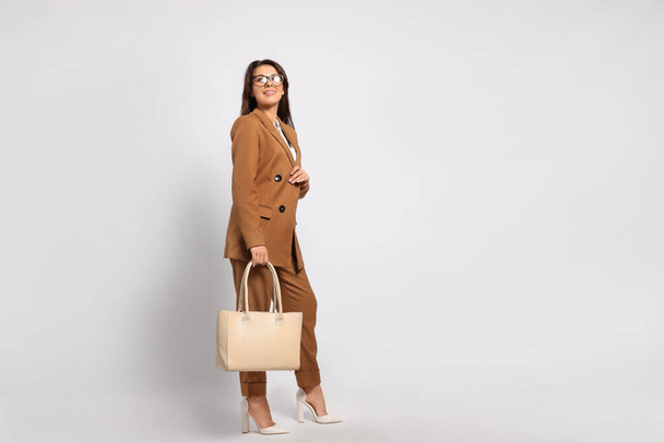 Young woman with stylish bag on white background - Foto, afbeelding