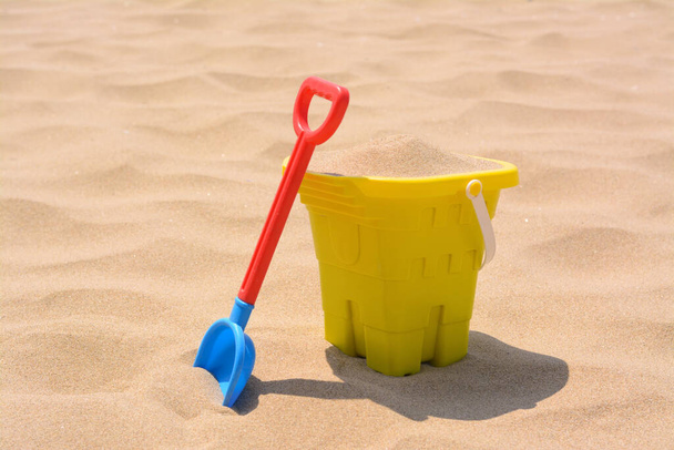 Plastic bucket and shovel on sand. Beach toys - 写真・画像