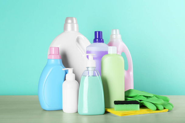 Different cleaning supplies and tools on wooden table against turquoise background - Foto, Imagem