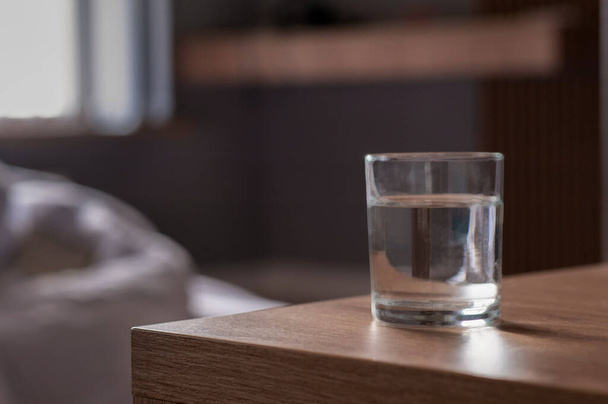 Glass of water on wooden table in room. Space for text - Foto, afbeelding