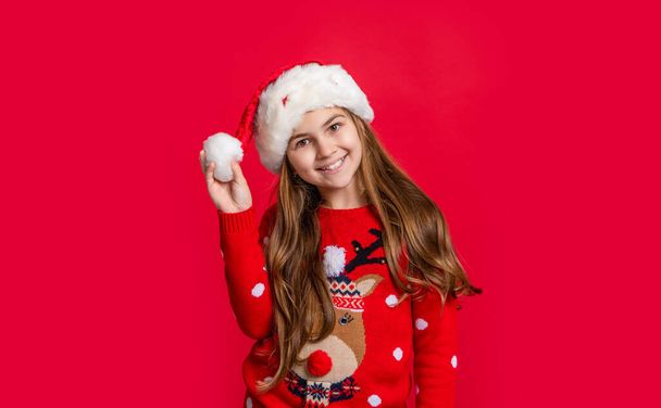 glad teen girl in santa claus hat on red new year background. new year teen girl in santa hat. teen girl wear sweater and santa hat at new year holiday. happy new year. - Photo, Image