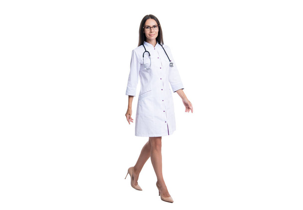 φωτογραφία της περπατούσας καρδιολόγου γυναίκα φορούν λευκό παλτό. καρδιολόγος γυναίκα γιατρός με στηθοσκόπιο. γυναίκα καρδιολόγος απομονωμένη σε λευκό φόντο. καρδιολόγος γυναίκα στο στούντιο. - Φωτογραφία, εικόνα