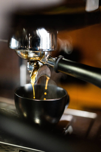 Máquina de café expresso fazendo café e derramando em uma xícara preta com vapor.   - Foto, Imagem
