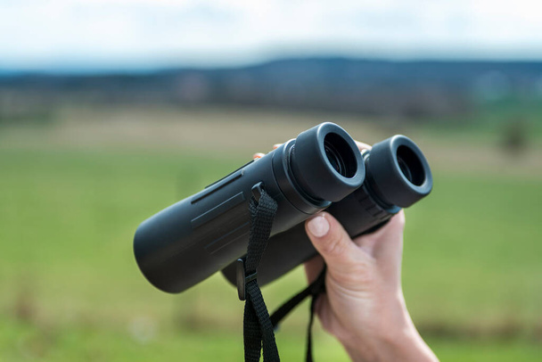 female hand holding a binoculars . - Foto, imagen