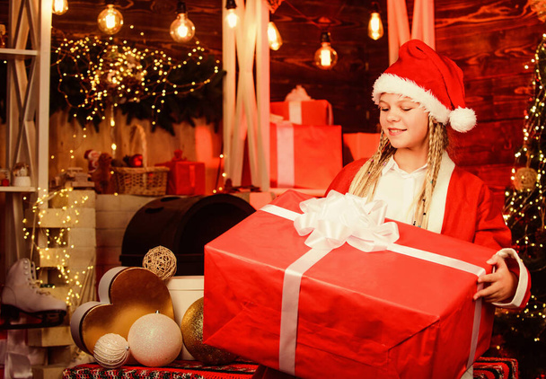magical joy. kid with present box. winter shopping sale. cheerful little girl at christmas tree. decorate home with joy. xmas mood. family holiday celebration. happy new year. child in red santa hat. - Foto, Imagen