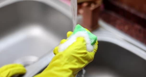 Руки домохозяйки в перчатках сжимают губку с мыльной пеной крупным планом 4К фильма замедленной съемки. Концепция мытья посуды - Кадры, видео