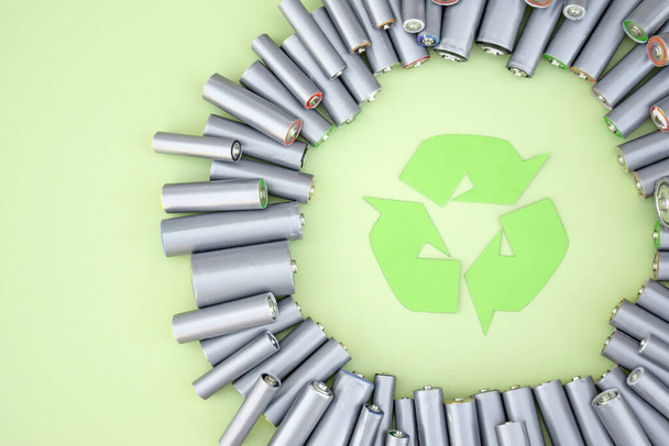 Batterie AA usate e corretto smaltimento di batterie tossiche per l'ambiente e il suolo su uno sfondo verde. Il concetto di lavorazione di oggetti nocivi e riciclabili. - Foto, immagini