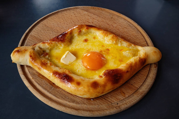 木製の板の上にアダリアン・カチャプリ-伝統的な。グルジア料理。卵とパン,チーズとバター. - 写真・画像