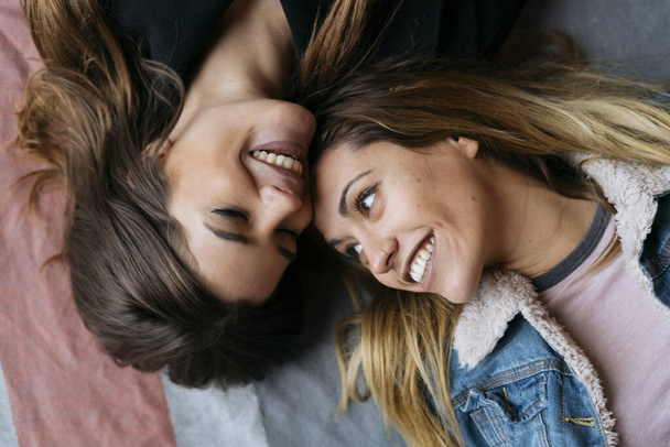 Young lesbian couple in love happily lying on the floor looking at each other - Foto, immagini