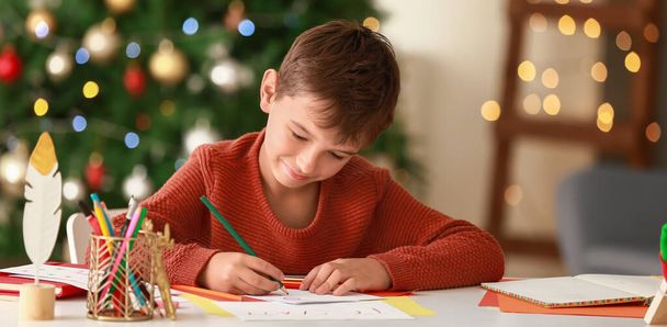 Χαριτωμένο αγόρι γράφει γράμμα στον Άγιο Βασίλη στο σπίτι την παραμονή των Χριστουγέννων - Φωτογραφία, εικόνα
