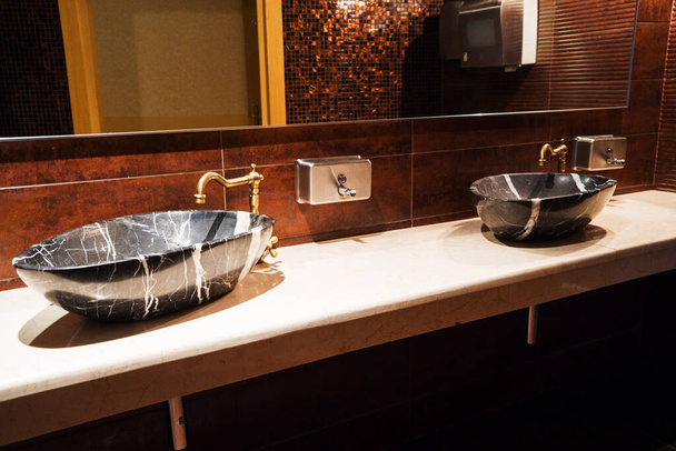 Schönes Waschbecken aus schwarzem Marmor mit gusseisernem Wasserhahn im Bad. - Foto, Bild