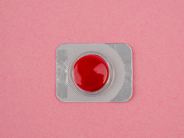 Rode pil op een roze achtergrond. Verzegelde rode pil. Close-up. - Foto, afbeelding
