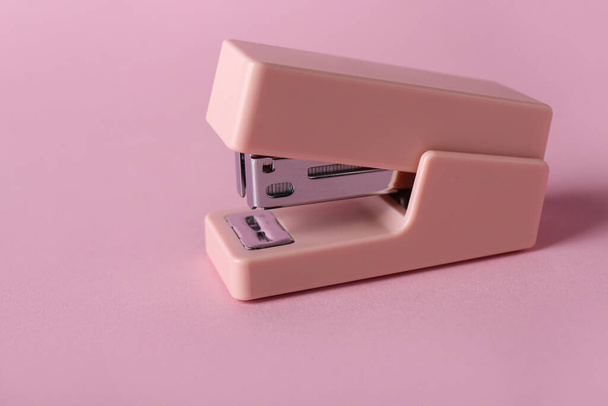 Офісний степлер на рожевому фоні
 - Фото, зображення
