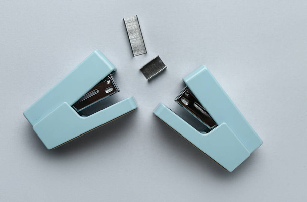 Office staplers and staples on light background - Φωτογραφία, εικόνα