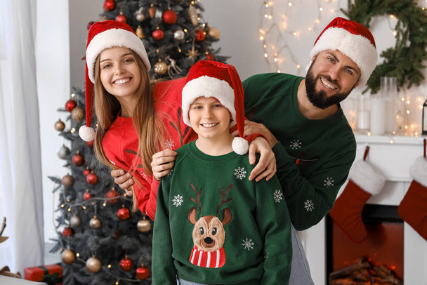 Happy parents with their little son in Santa hats at home on Christmas eve - Фото, зображення