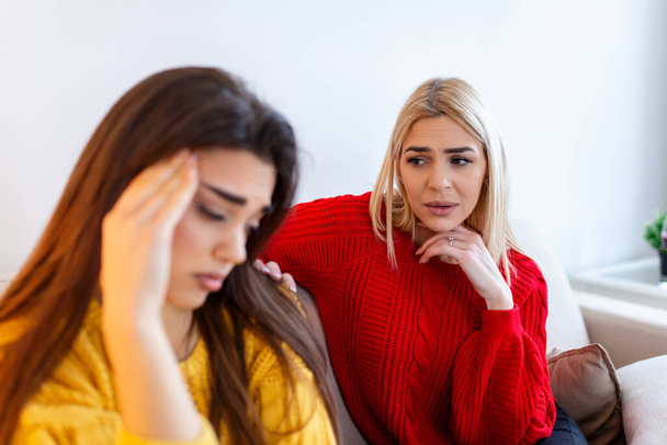 Sad women and supporting friends trying to solve a problem. Two sad diverse women talking at home. Female friends supporting each other. Problems, friendship and care concept - Foto, imagen