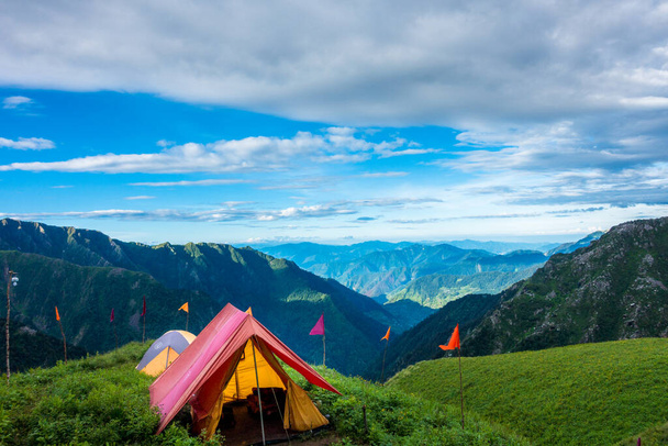 14 juli 2022, Himachal Pradesh India. Tenten en kampen met prachtige landschappen, vallei en bergen op de achtergrond. Shrikhand Mahadev Kailash Yatra in de Himalaya. - Foto, afbeelding