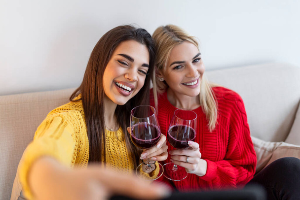 Excited friends taking selfie and laughing. Indoor shot of two emotional caucasian girls. Two adult woman making selfies with funny faces. Two female friends taking a selfie - Foto, Bild