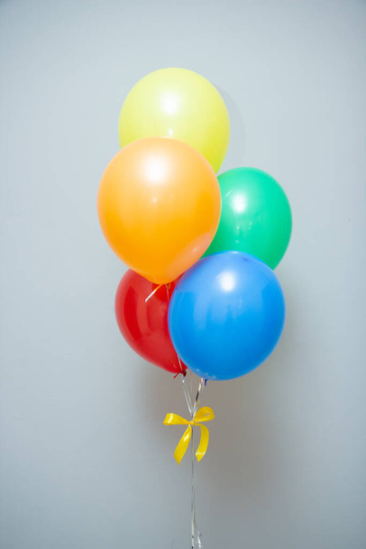 a bouquet of colorful balloons for the holiday on the background of the wall - Fotó, kép