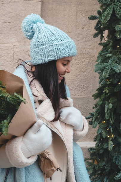zima strój uśmiechnięta ładna kobieta spacery na zewnątrz gospodarstwa Boże Narodzenie drzewo bukiet - Zdjęcie, obraz