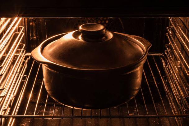 Dark cast iron pot with lid on in the electric oven - Φωτογραφία, εικόνα