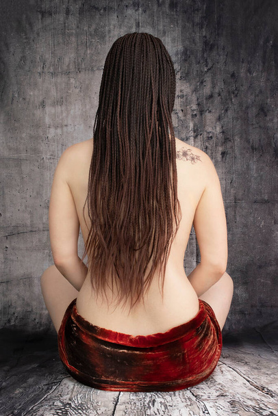 Beauty and spa. A Caucasian woman's back with African braids and a discreet tattoo - Foto, immagini