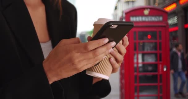 Primer plano de la mensajería de texto de manos femeninas en el teléfono inteligente mientras está en el centro de Londres. Tight shot de mujer usando el teléfono móvil en la calle durante su viaje de negocios a Inglaterra. 4k - Metraje, vídeo