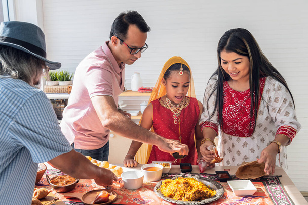 an Indian family standing in the kitchen They help each other prepare the food that they ordered. Arrange in a container placed on the table, to family and Indian food concept. - Photo, Image