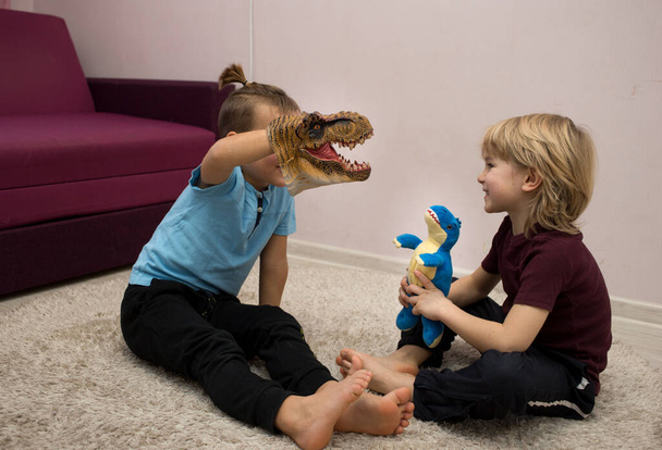 esikoulupojat pelata roolipelejä dinosaurus leluja istuu lattialla. Viestintä ystävien kanssa, ystävyys veljesten välillä, iloinen lapsuus. valikoiva kohdentaminen. viihdettä lapsille. - Valokuva, kuva