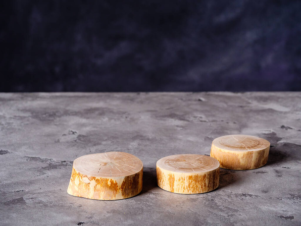 Slices of wood of tree for product presentation lies on a gray concrete surface - Foto, Imagem