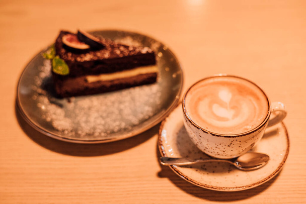 Egy csésze kávé tejjel, barna háttérrel. Forró cappuccino az asztalon. Kiváló minőségű fénykép - Fotó, kép