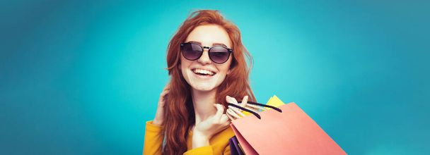 Shopping Concept - Close up Portrait young beautiful attractive redhair girl smiling looking at camera with shopping bag. Blue Pastel Background. Copy space. - Photo, Image