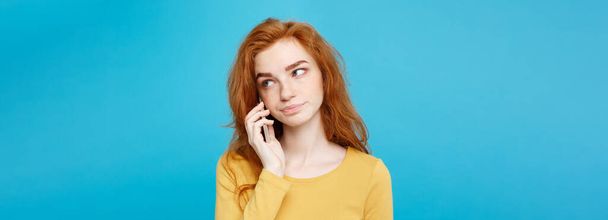 Lifestyle Portrait of cheerful happy ginger red hair girl with shocking and stressful expression while talking with friend by mobile phone. Isolated on Blue Pastel Background. Copy space. - Fotó, kép