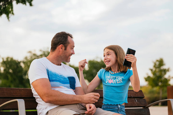 Padre entregando un teléfono inteligente a su hijita. - Foto, Imagen