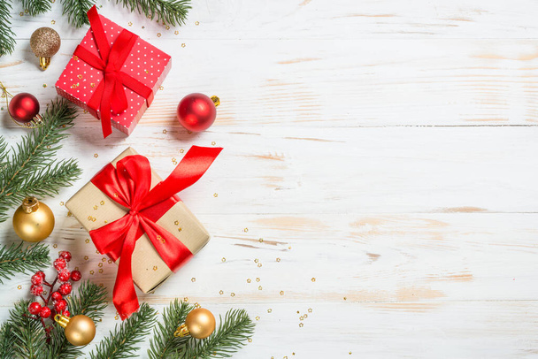 Karácsonyi ajándékdoboz piros szalaggal és ünnepi dekorációval. Felülnézet fehér fából készült asztalnál fénymásoló hellyel. - Fotó, kép
